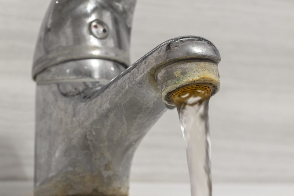Hard water flows from an old tap